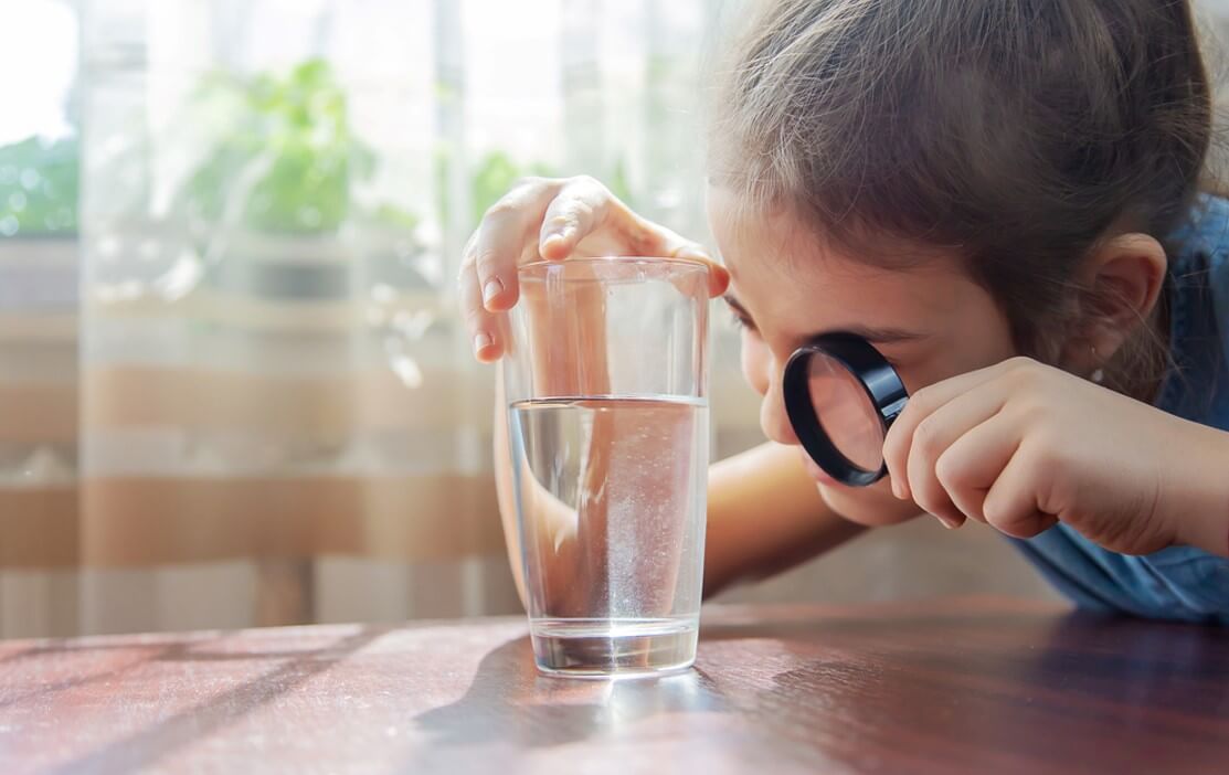 child looking with magnifying glass in the glass