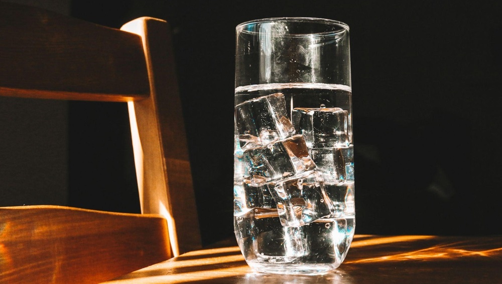 A glass of ice water on a wooden table